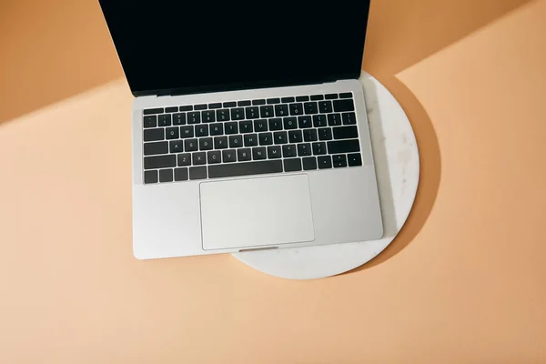 Vue du dessus de l'ordinateur portable sur panneau de marbre blanc sur fond beige — Photo de stock