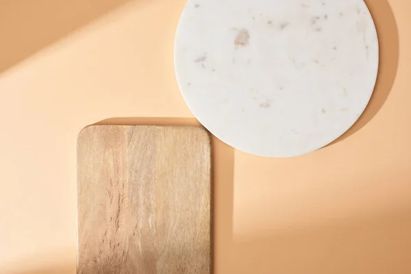 Vista superior de tableros de madera y mármol sobre fondo beige - foto de stock