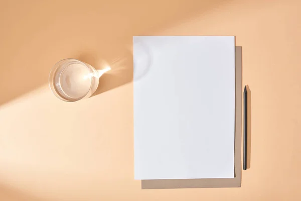 Top view of sheets of paper, pencil and glass of water on beige background — Stock Photo