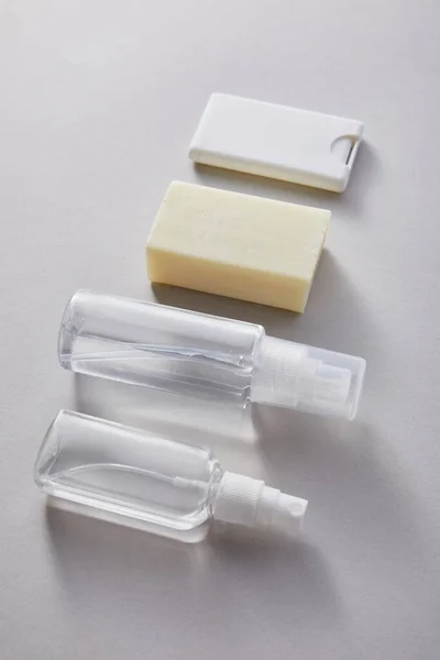 Flat lay with hand sanitizer in spray bottles and antibacterial soap on grey background — Stock Photo