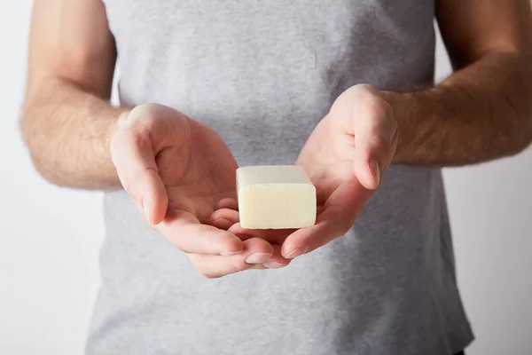 Partial view of man holding soap on grey background background — Stock Photo