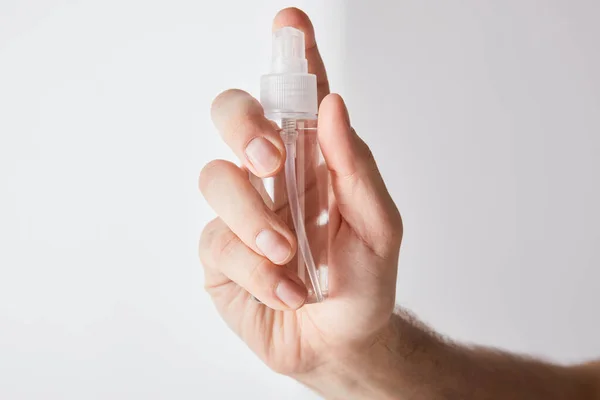 Vista ritagliata di uomo tenendo mano igienizzante in bottiglia spray su sfondo grigio — Foto stock