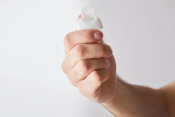 Cropped view of man holding hand sanitizer on grey background — Stock Photo