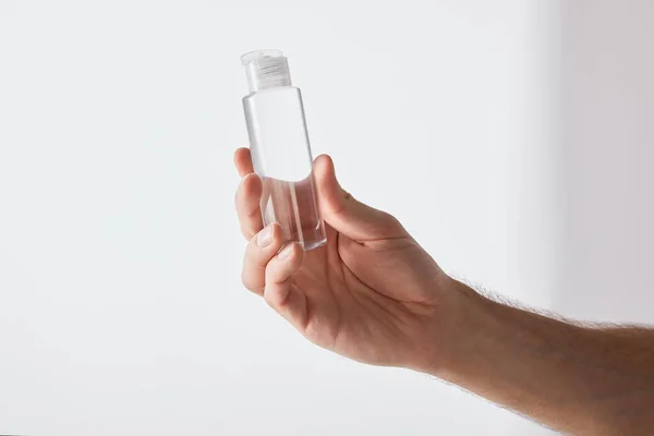 Cropped view of man holding hand sanitizer on grey background — Stock Photo