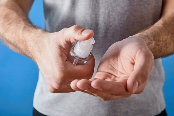 Abgeschnittene Ansicht des Mannes mit Gel-Händedesinfektionsmittel in Flasche isoliert auf blau — Stockfoto