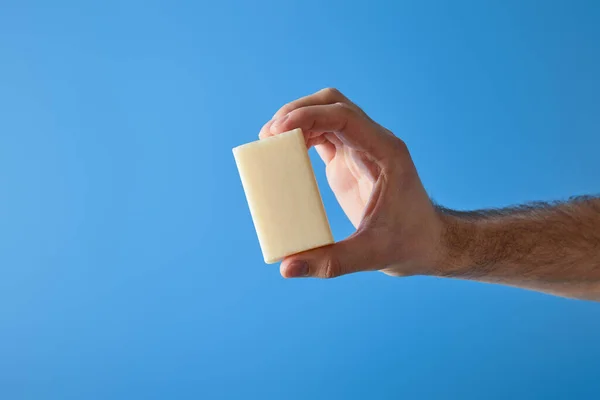 Cropped view of man holding soap isolated on blue — Stock Photo