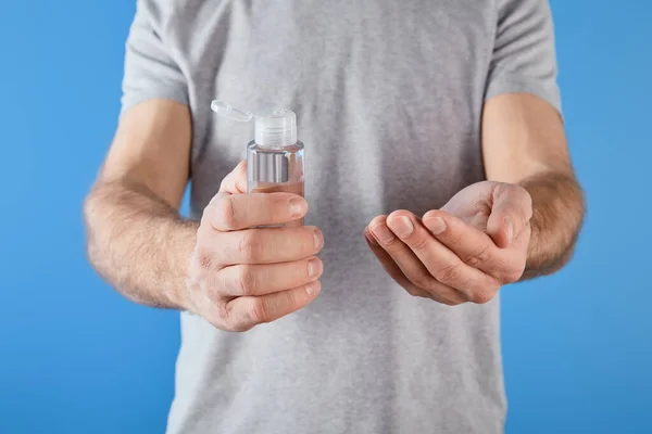 Cropped view of man holding gel hand sanitizer in bottle isolated on blue — Stock Photo