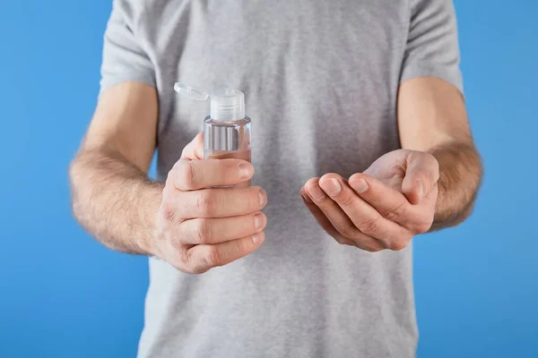 Abgeschnittene Ansicht des Mannes mit Gel-Händedesinfektionsmittel in Flasche isoliert auf blau — Stockfoto