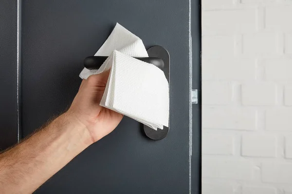 Partial view of man cleaning metal door handle with napkin — Stock Photo