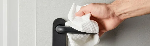 Partial view of man cleaning metal door handle with napkin, panoramic shot — Stock Photo