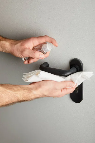 Partial view of man cleaning metal door handle with antiseptic and napkin — Stock Photo