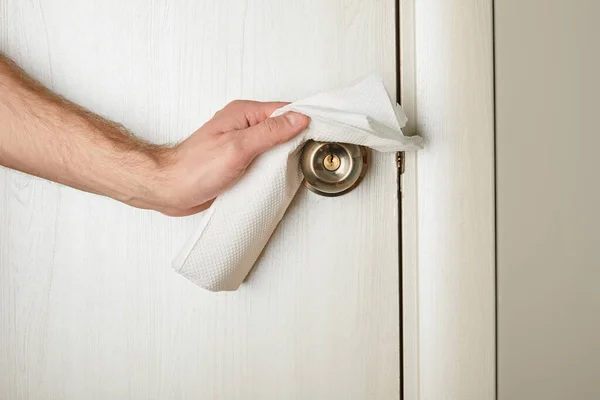 Partial view of man cleaning metal door handle with napkin — Stock Photo