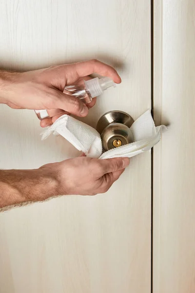 Vue recadrée de l'homme désinfectant poignée de porte avec antiseptique et serviette — Photo de stock