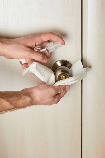 Vista recortada del hombre desinfectando la manija de la puerta con antiséptico y servilleta - foto de stock