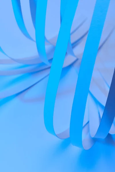 Закрыть вид изогнутых красочных полос бумаги на неоновом синем фоне — стоковое фото