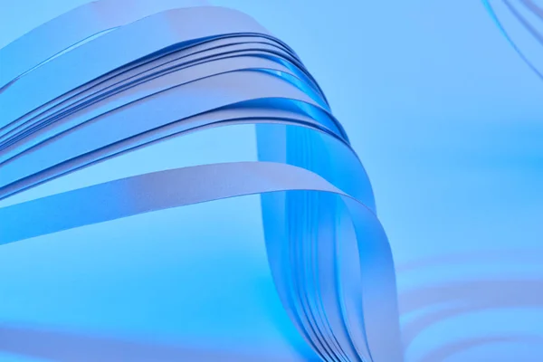 Close up view of curved colorful paper stripes on neon blue background — Stock Photo