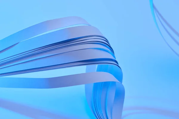 Close up view of curved colorful paper stripes on neon blue background — Stock Photo