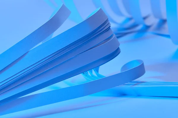 Close up view of curved paper stripes on neon blue background — Stock Photo