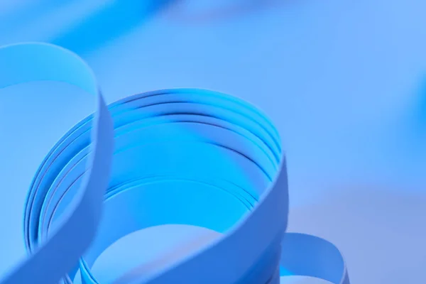 Close up vista de listras de papel curvo no fundo azul néon — Fotografia de Stock