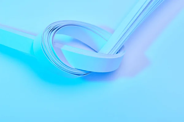 Vista de cerca de las rayas de papel sobre fondo azul neón - foto de stock