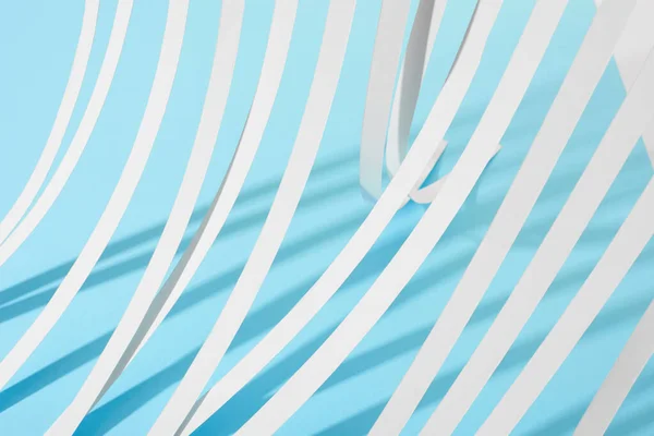 Vista de cerca de las rayas de papel blanco sobre fondo azul - foto de stock