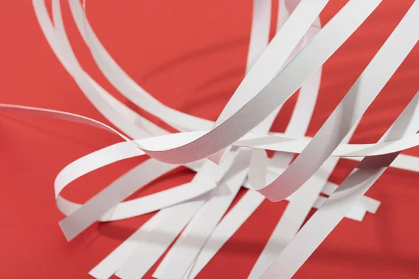 Vue rapprochée des bandes de papier blanc sur fond rouge — Photo de stock