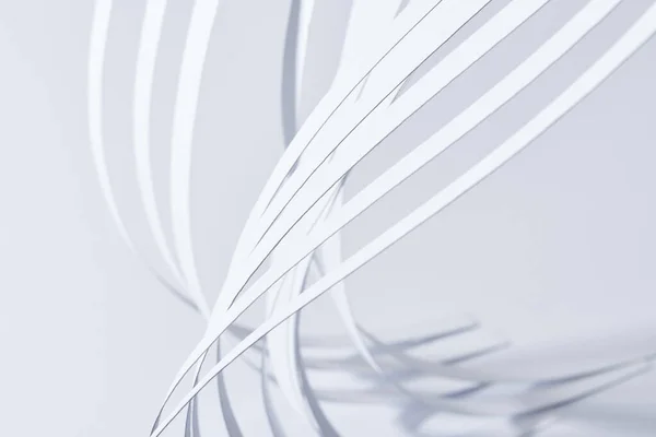 Vista de cerca de las rayas de papel curvadas sobre fondo blanco - foto de stock