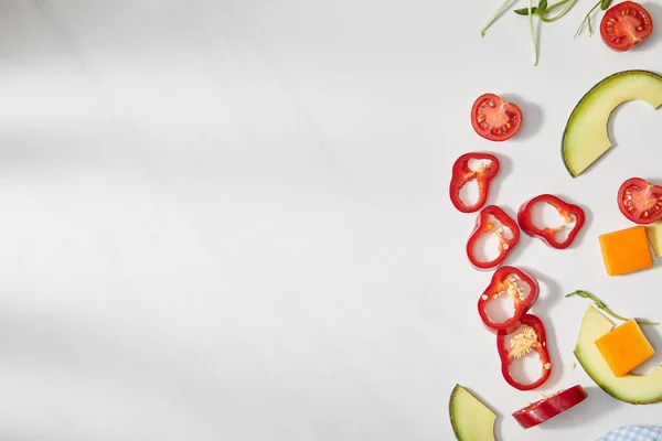 Draufsicht auf geschnittene Chilischoten, Kürbisse und Kirschtomaten mit Avocadoscheiben auf weißem Hintergrund — Stockfoto