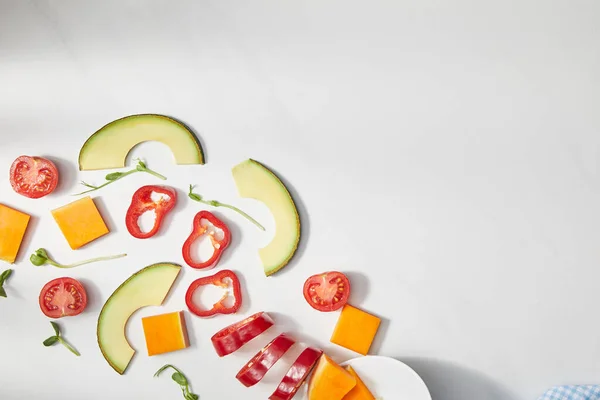 Vista superior de microgreens, chile cortado, calabaza y tomates cherry con rodajas de aguacate sobre fondo blanco - foto de stock