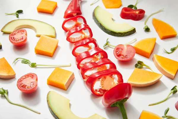 Hochwinkelblick auf Mikrogemüse, geschnittenes reifes Gemüse und Avocadoscheiben auf weißem Hintergrund — Stockfoto