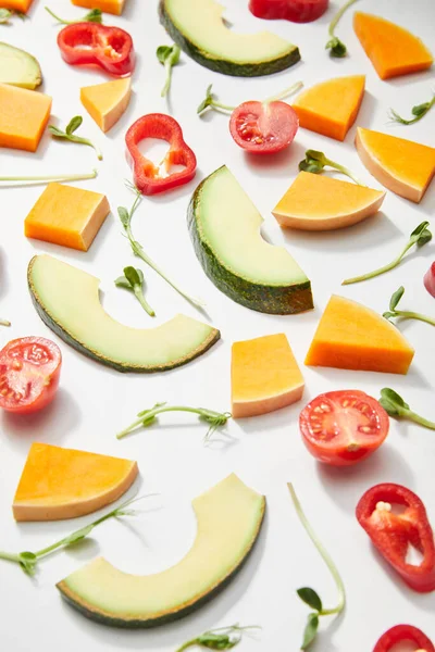 High angle view of microgreens, cut fresh vegetables and ripe avocado slices on white background — Stock Photo