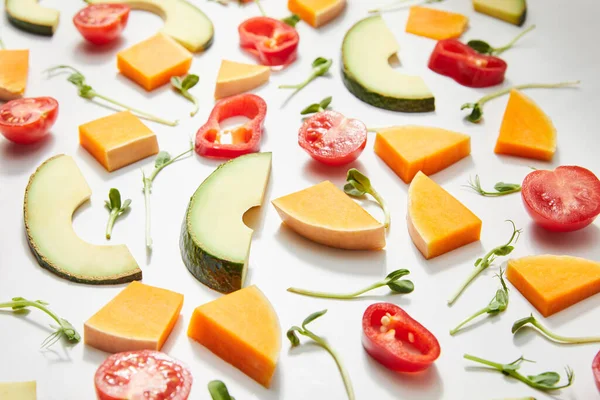 Foco seletivo de microverdes, corte tomates cereja maduros, pimentão de pimentão, abóbora e fatias de abacate no branco — Fotografia de Stock