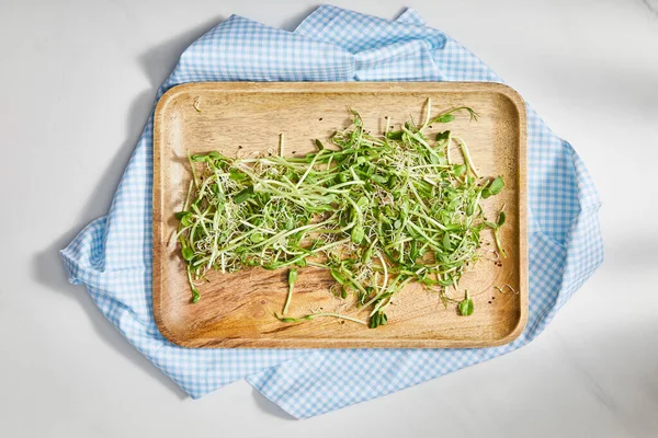 Top view of cutting board with microgreens on plaid cloth on white background — Stock Photo