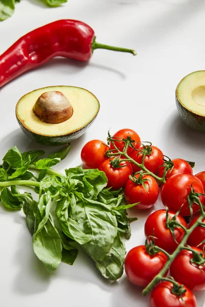 Pomodori ciliegia, peperoncino, basilico e avocado a metà su fondo bianco — Foto stock