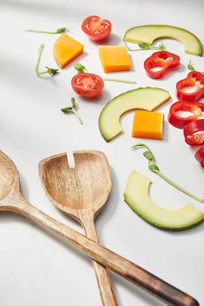 Hochwinkelaufnahme von Spateln in der Nähe von geschnittenem Gemüse und Avocadoscheiben auf weißem Hintergrund — Stockfoto