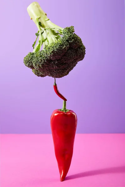 Broccoli on chili peppers on purple and pink — Stock Photo