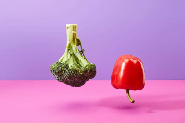 Upside down raw bell pepper and broccoli on purple and pink — Stock Photo