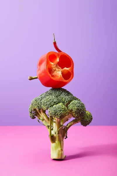 Ají y la mitad fresca de pimiento sobre brócoli en púrpura y rosa - foto de stock