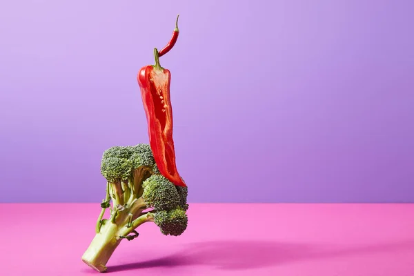 Hälfte Chilischote auf reifem Brokkoli auf violett und rosa — Stockfoto