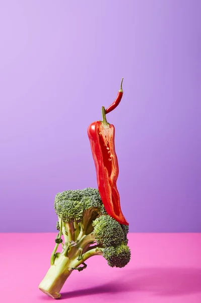 Hälfte Chilipfeffer auf rohem Brokkoli auf violett und rosa — Stockfoto
