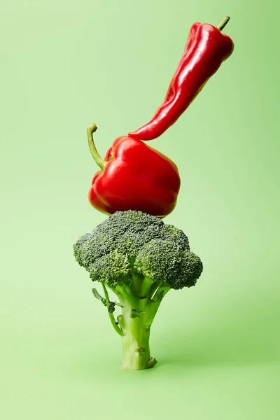 Chili and bell peppers on broccoli on green — Stock Photo