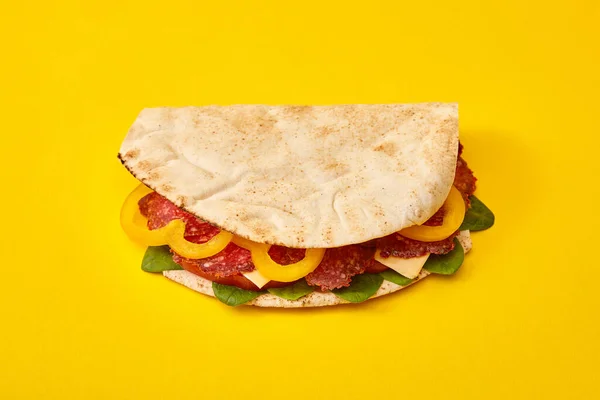 Panino fresco con salame, pita, verdure e formaggio su fondo giallo — Foto stock