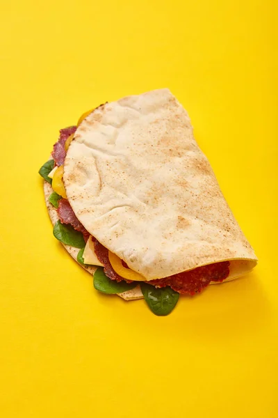 Sándwich fresco con salami, pita, verduras y queso sobre fondo amarillo - foto de stock