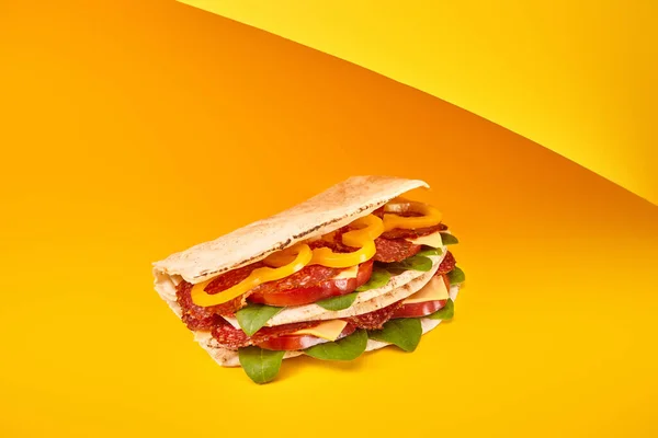 Свежий сэндвич с салями, пита, овощи и сыр на желтом фоне — стоковое фото