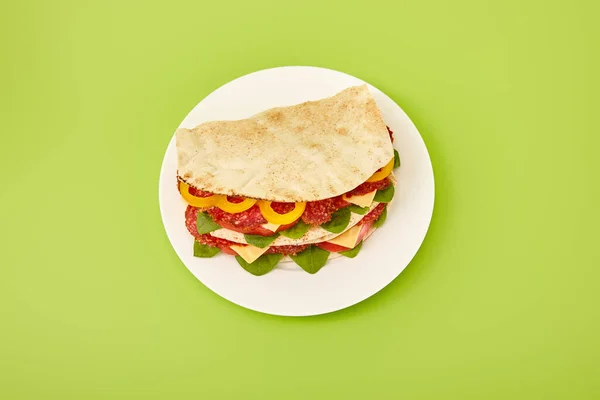 Panino fresco con salame, pita, verdure e formaggio su fondo verde — Foto stock