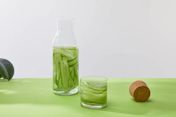 Corcho, botella y vaso con bebida hecha de pepinos en rodajas aislados en gris - foto de stock