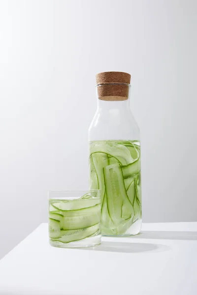 Bottle with cork and glass with drink made of sliced cucumbers isoated on grey — Stock Photo