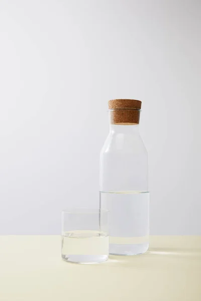 Botella con corcho y vaso lleno de agua sobre aislado sobre gris - foto de stock