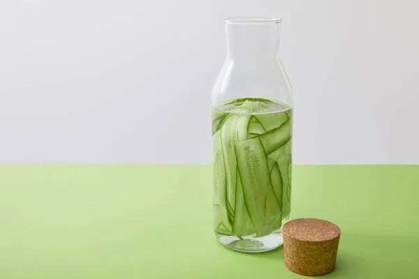 Cork and bottle with water and sliced cucumbers isolated on grey — Stock Photo