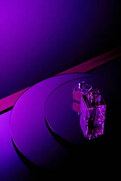 Frascos de perfume roxo na superfície do espelho redondo com fundo violeta escuro — Fotografia de Stock